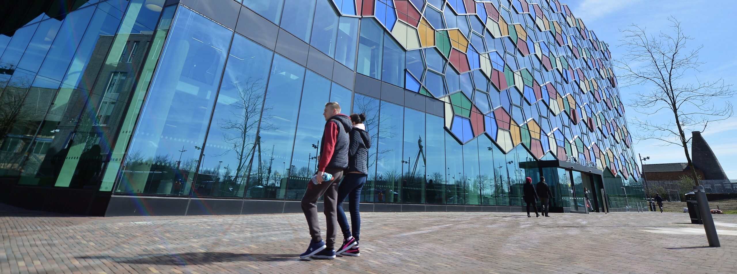 Two people walking in front of glass building with geometric design