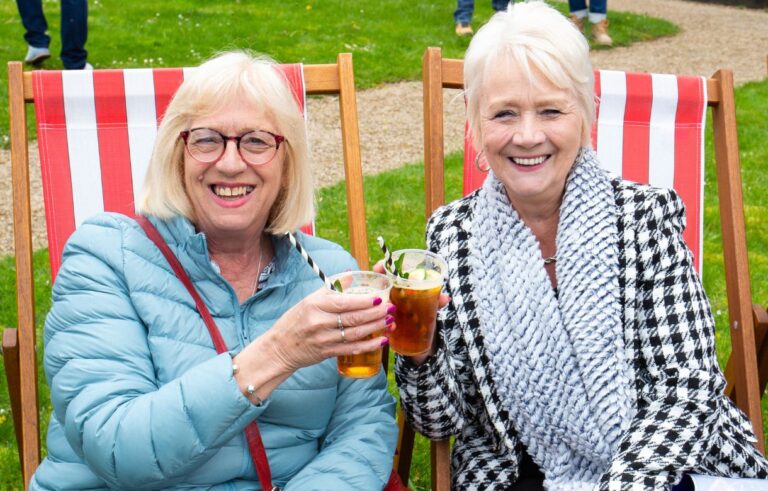 Two women smiling holding glasses of Pimm's