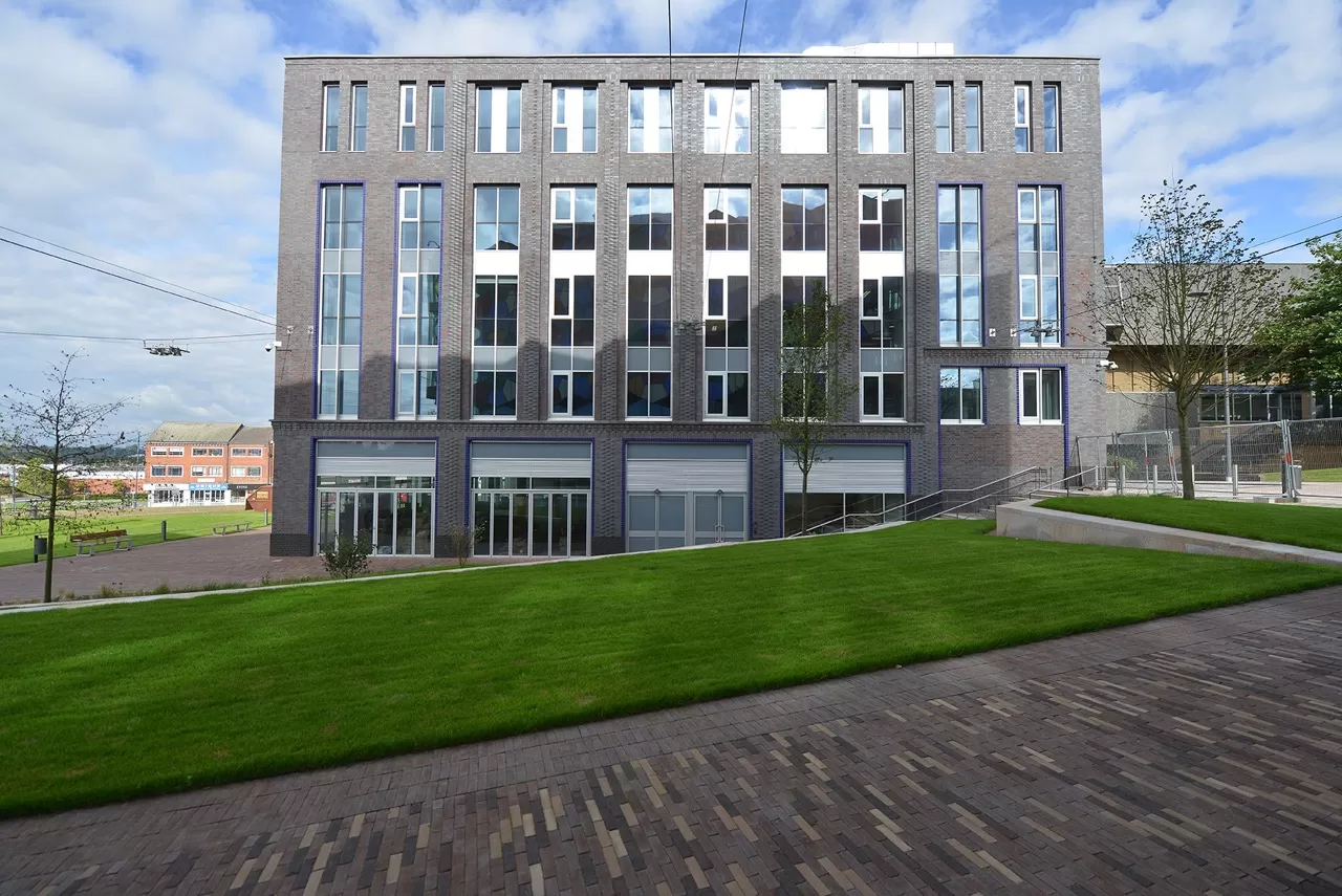 Large grey square building with a swathe of grass in front