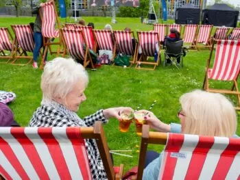 two women in deck chairs cheers glasses of pimms