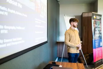 Young man stands in front of a projection screen